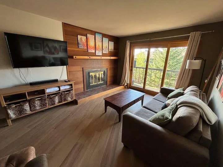 Living room with sofa, fireplace, television, and balcony doors