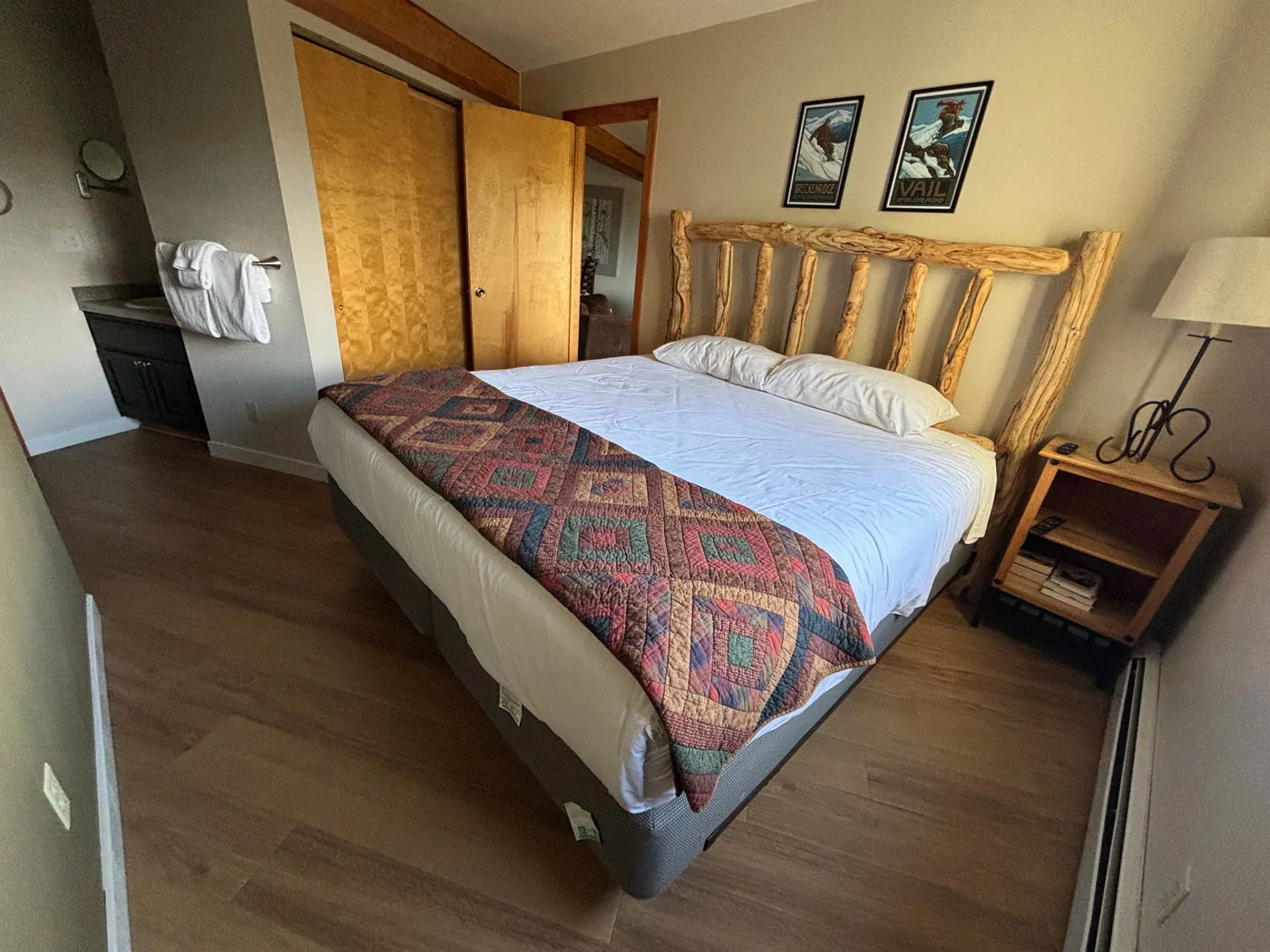 Primary bedroom with king bed, wood headboard, quilt, nightstand, and warm mountain decor
